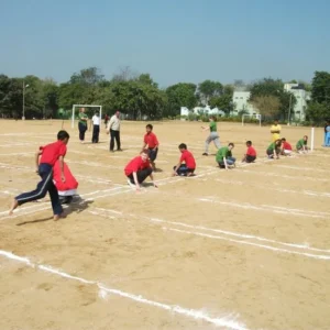 Children playing kho-kho during a school sports event on sand court